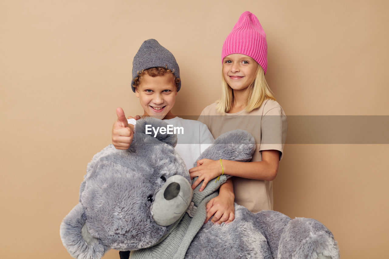 Portrait of cute girl with stuffed toy against beige background