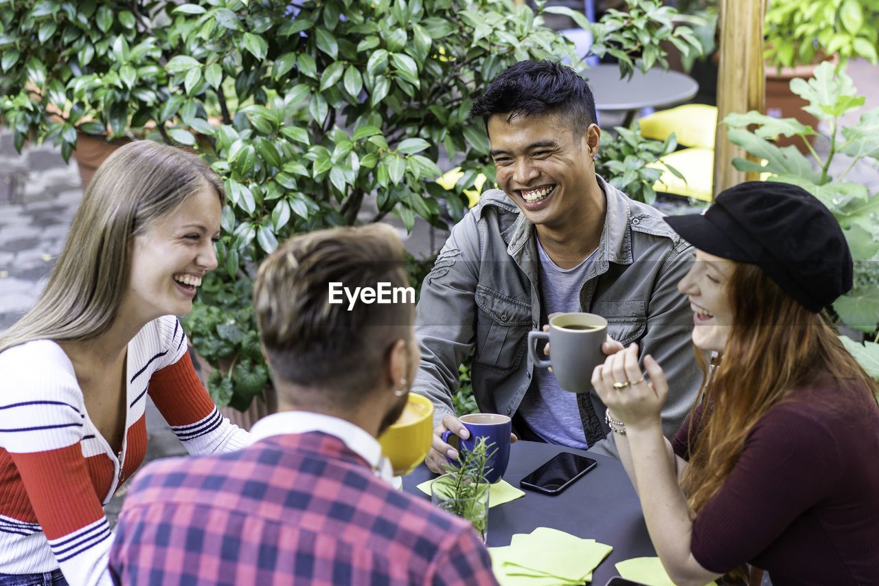 High angle view of happy friends sitting at cafe