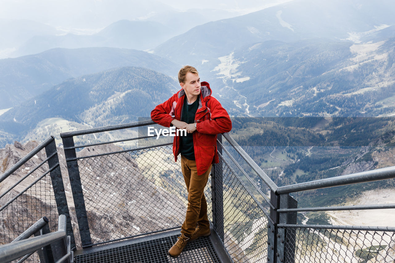 Millennial guy enjoys mountain views of alps from observation deck