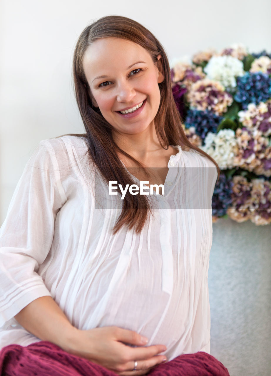 PORTRAIT OF A SMILING YOUNG WOMAN SITTING