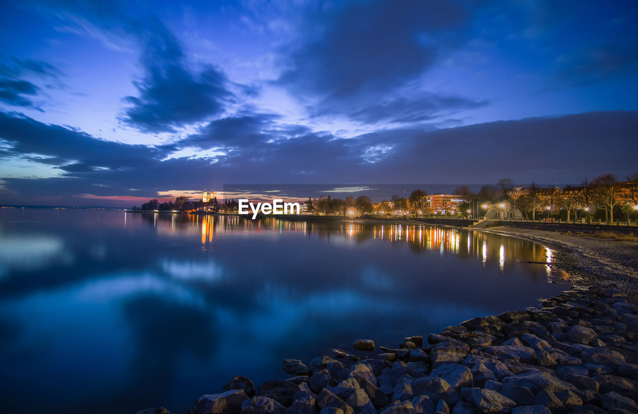 Scenic view of illuminated reflection against sky at sunset