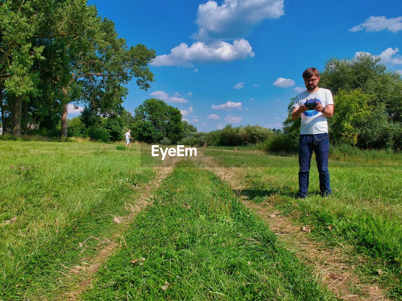 REAR VIEW OF MAN STANDING ON FIELD AGAINST SKY