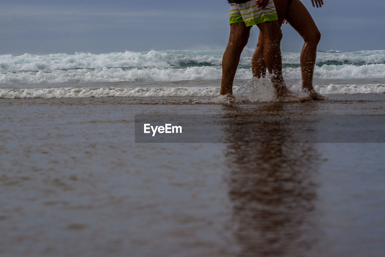 Low section of man standing on beach