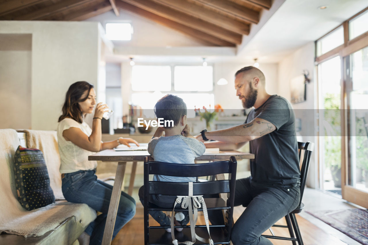 Family of three sitting at dining table in house