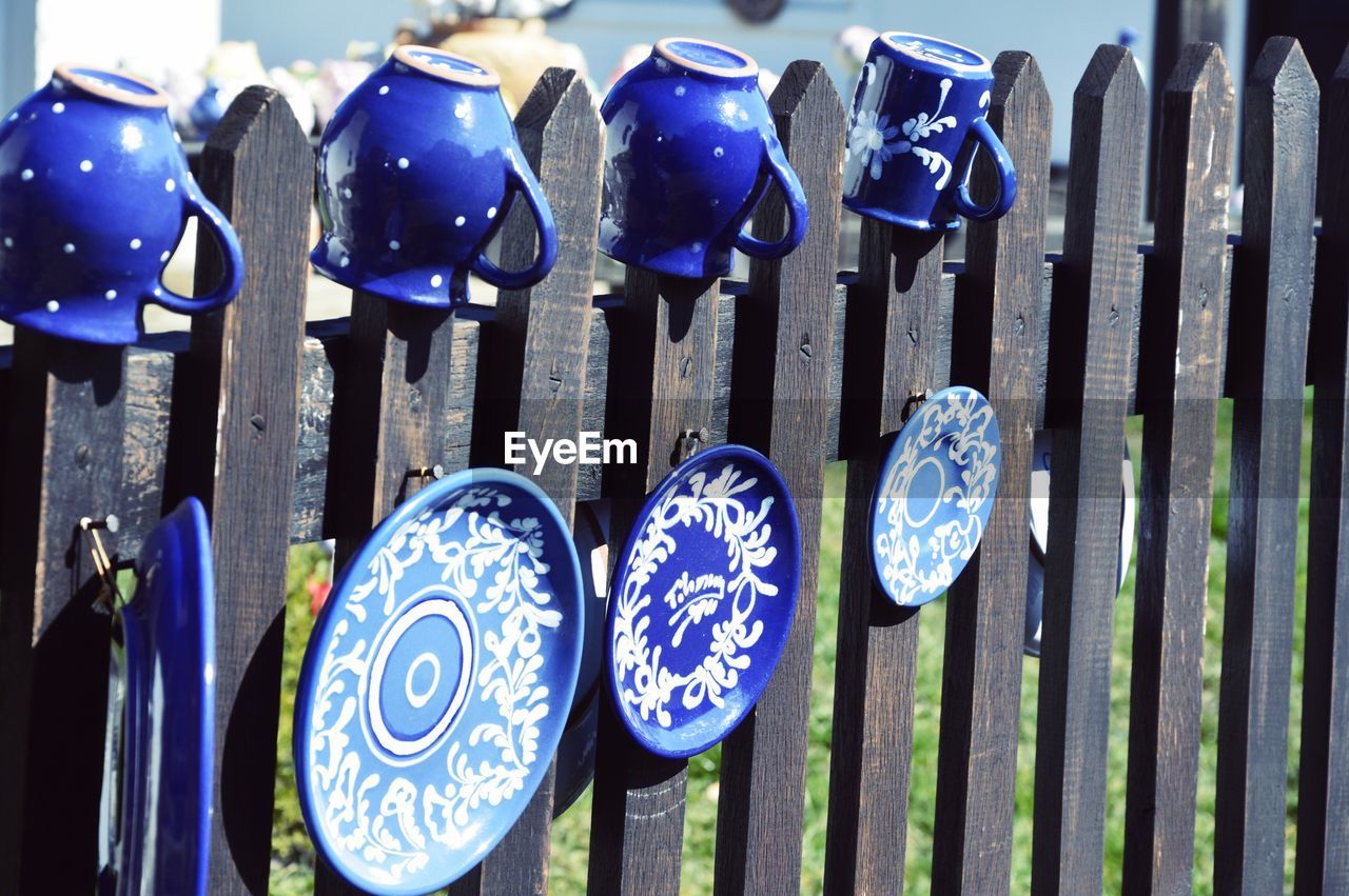 Blue mugs and plates on wooden fence