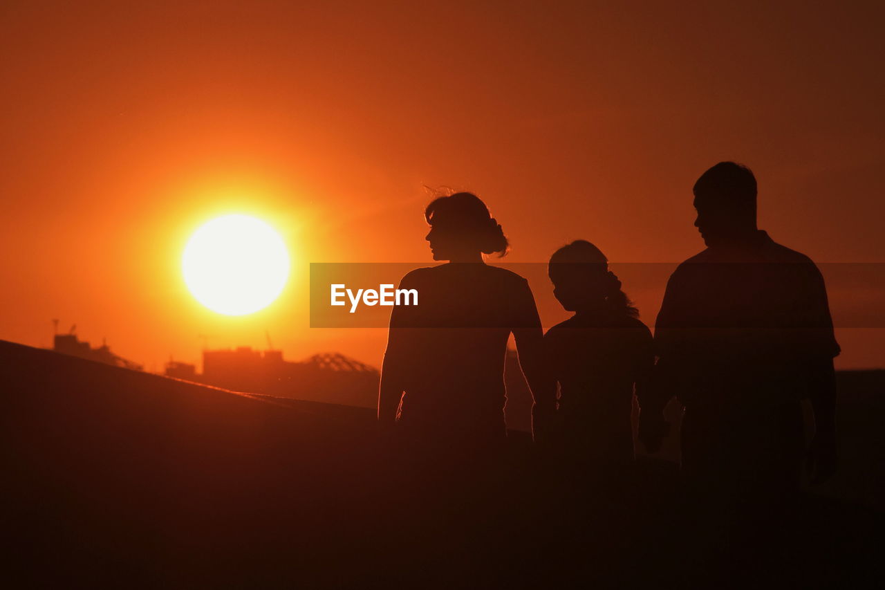 SILHOUETTE MEN STANDING AGAINST ORANGE SKY