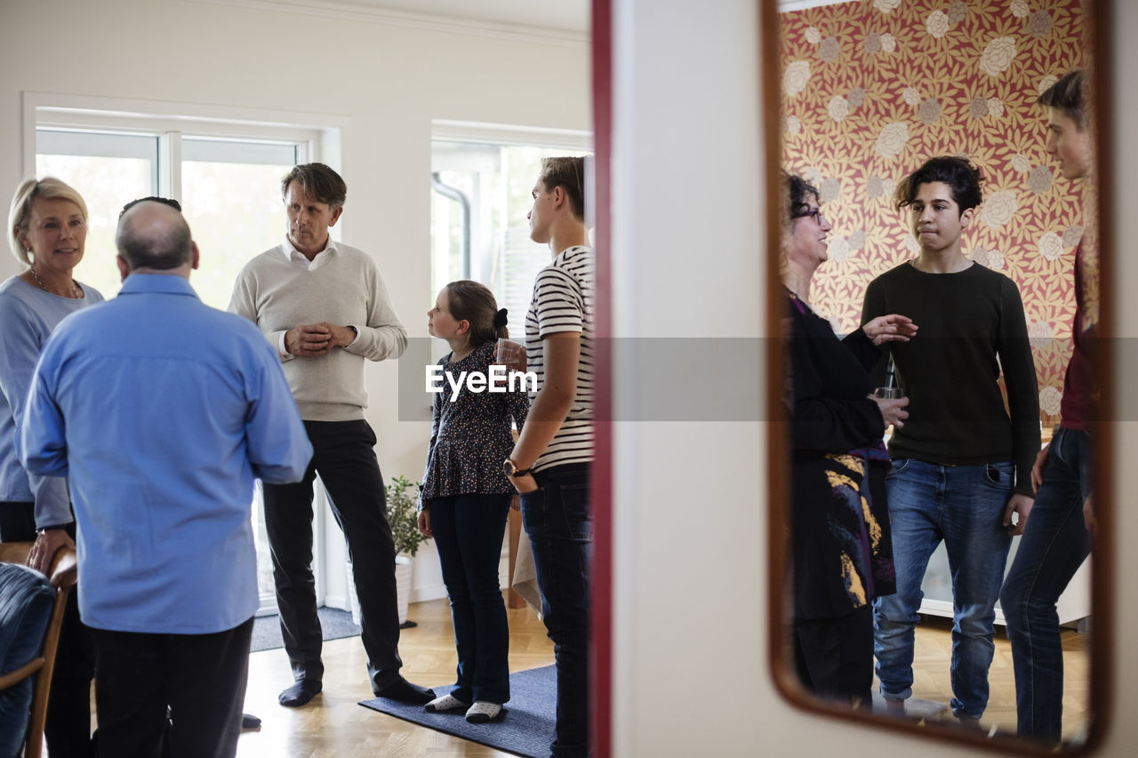 Multi-ethnic friends and family talking while having drink at social gathering