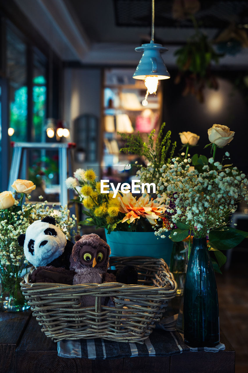 Soft toys in basket and flower pots arranged on table at cafe