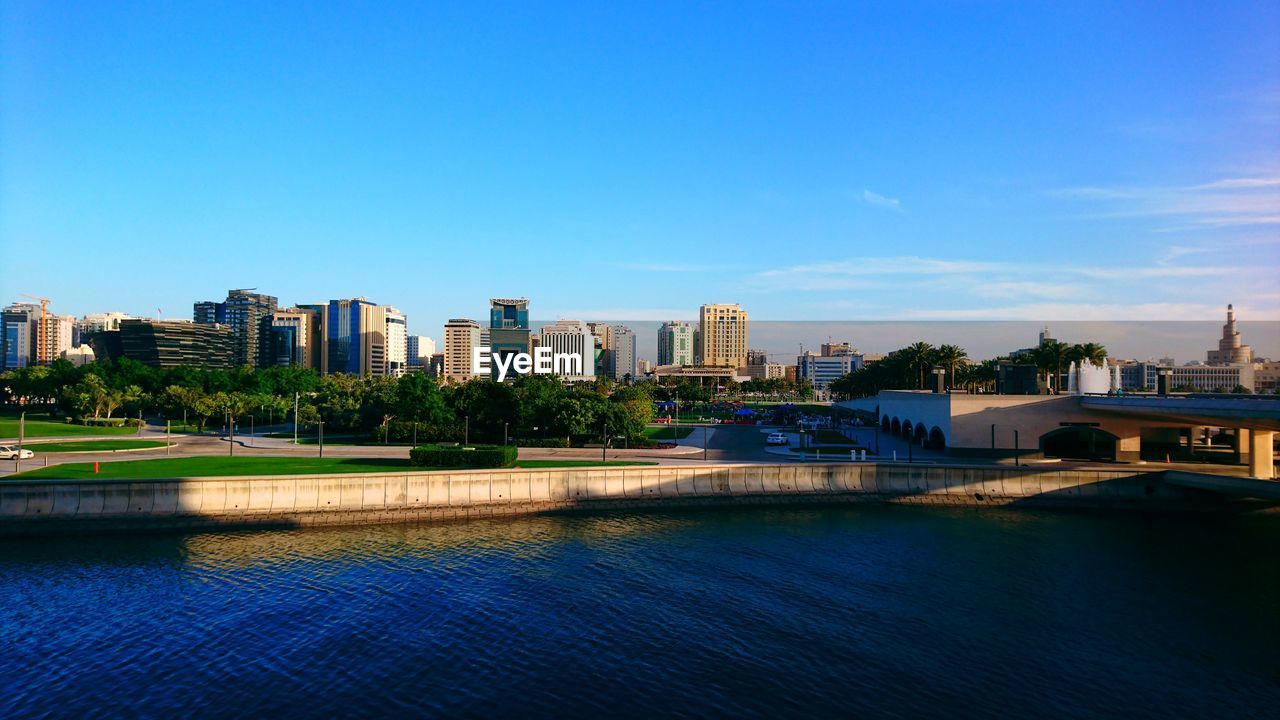 RIVER AMIDST BUILDINGS AGAINST BLUE SKY