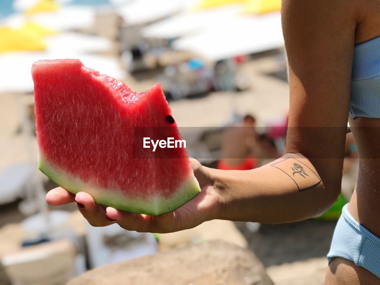 Midsection of teenage girl holding watermelon slice at beach