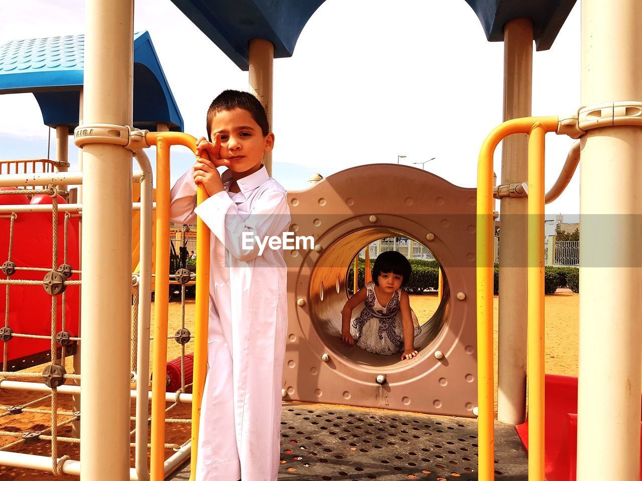 Portrait of cute boy and girl on outdoor play equipment at playground