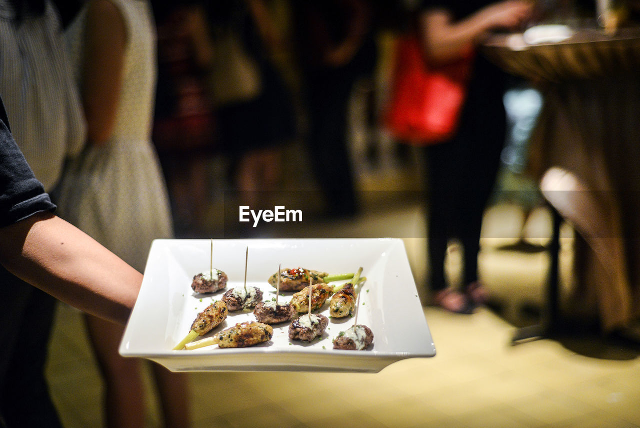 Cropped hand holding plate with appetizers