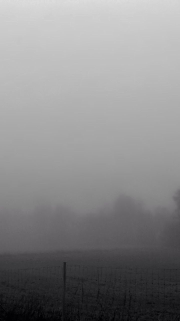 Chainlink fence against clear sky on foggy day