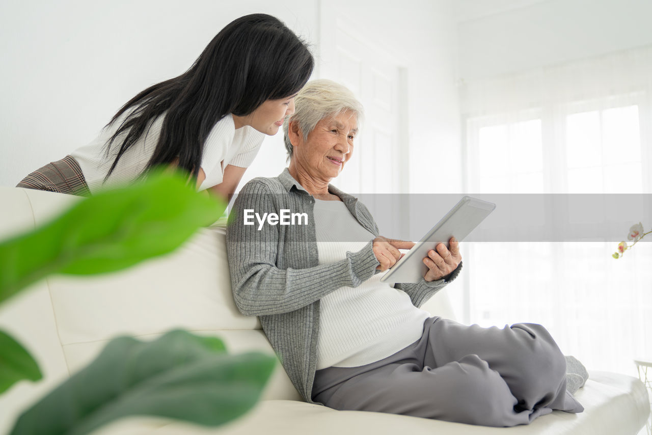 Woman using phone while sitting on laptop