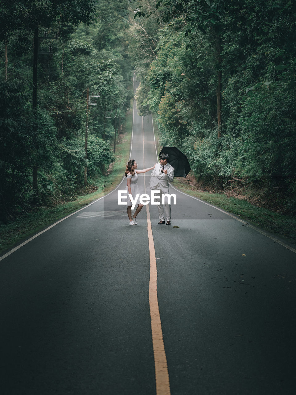 People walking on road along trees