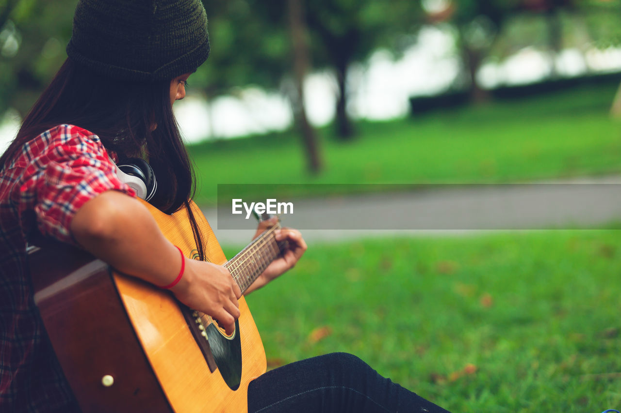 Woman playing guitar on field