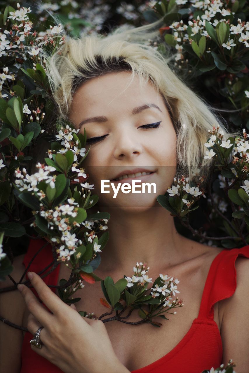 Close-up of smiling beautiful woman by flowering plants