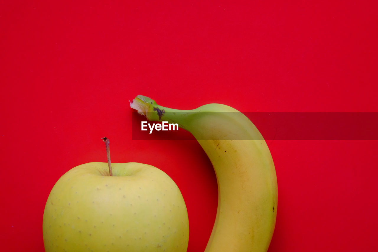 Close-up of apple  and banana on red background