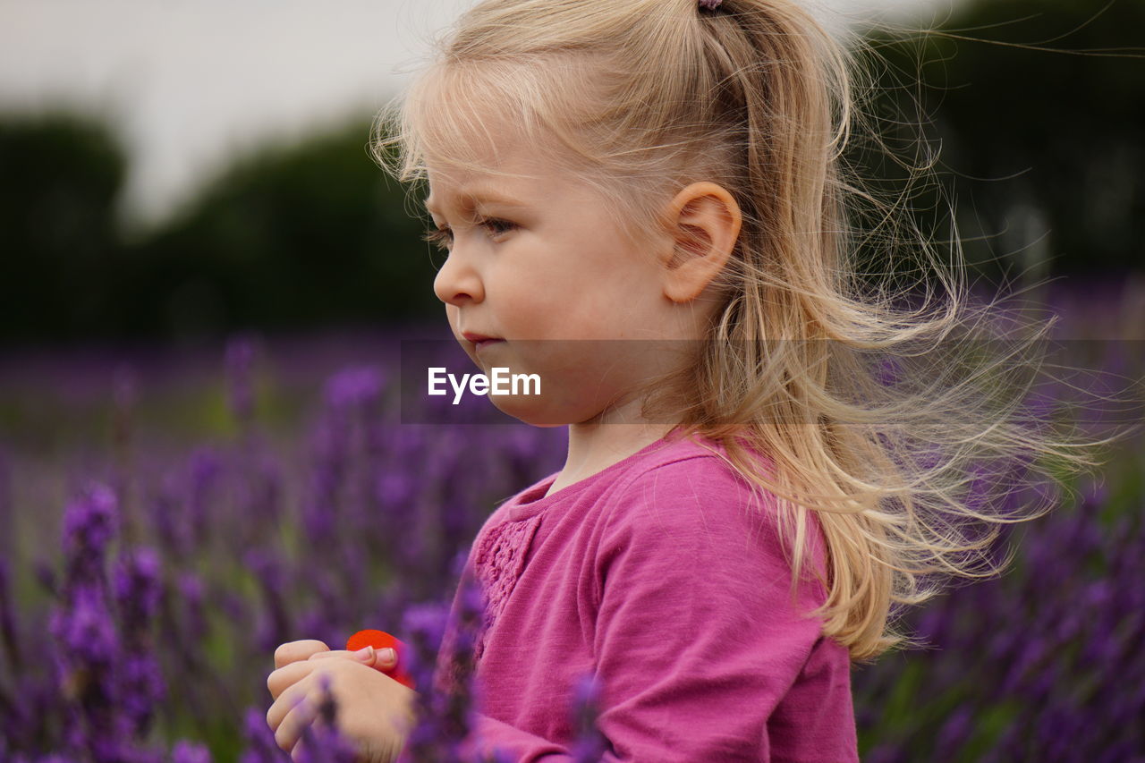 Close-up of girl amidst flowers on field