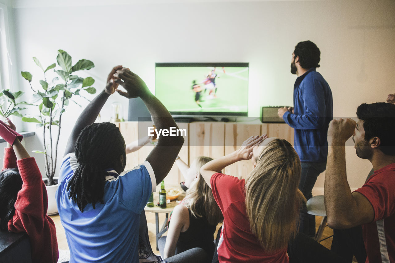 Fans cheering while watching soccer match on tv at home