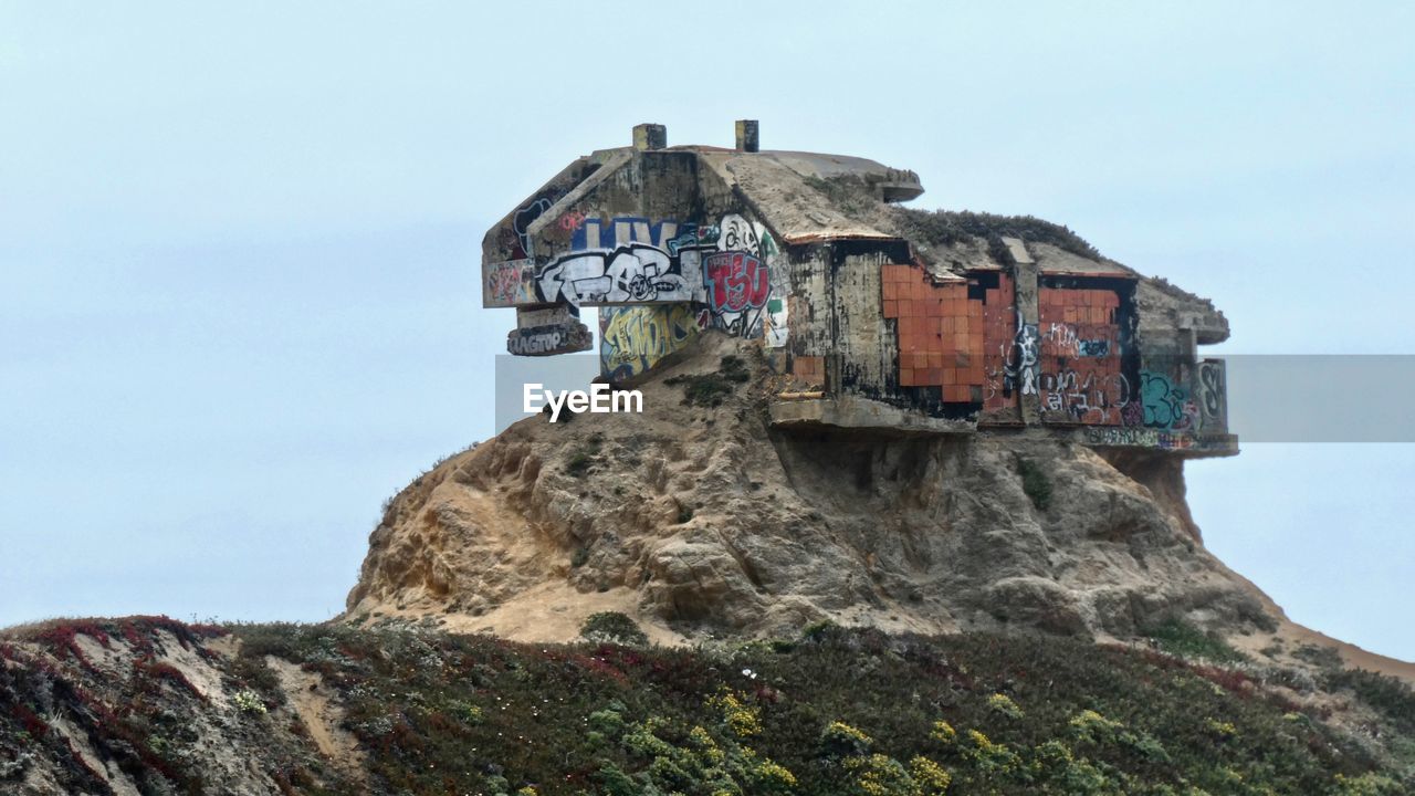 LOW ANGLE VIEW OF OLD BUILDING ON ROCK