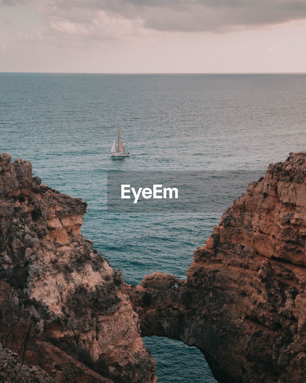 Scenic view of sea and rock formations against cloudy sky