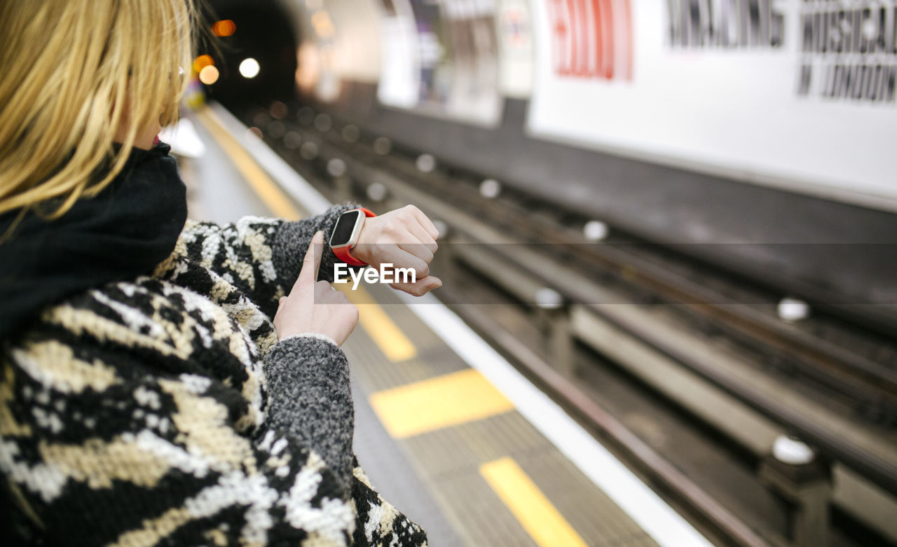 Young woman looking on her smartwatch waiting for the subway