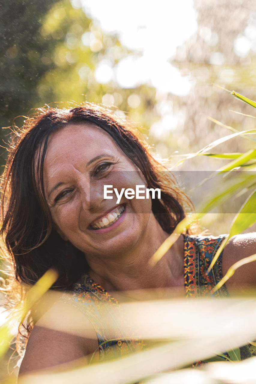 Portrait of beautiful middle aged woman in front of a fountain in a park at sunset