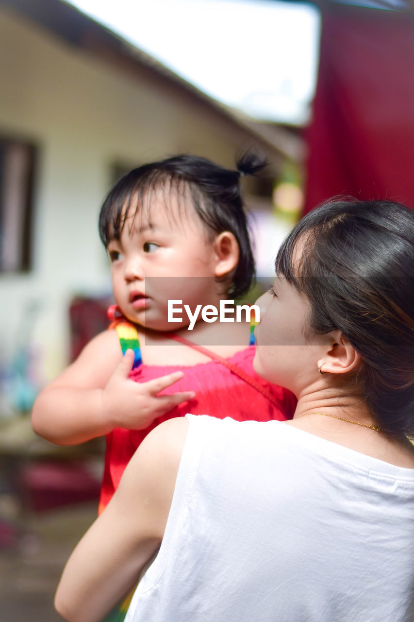 Close-up of mother carrying daughter at home