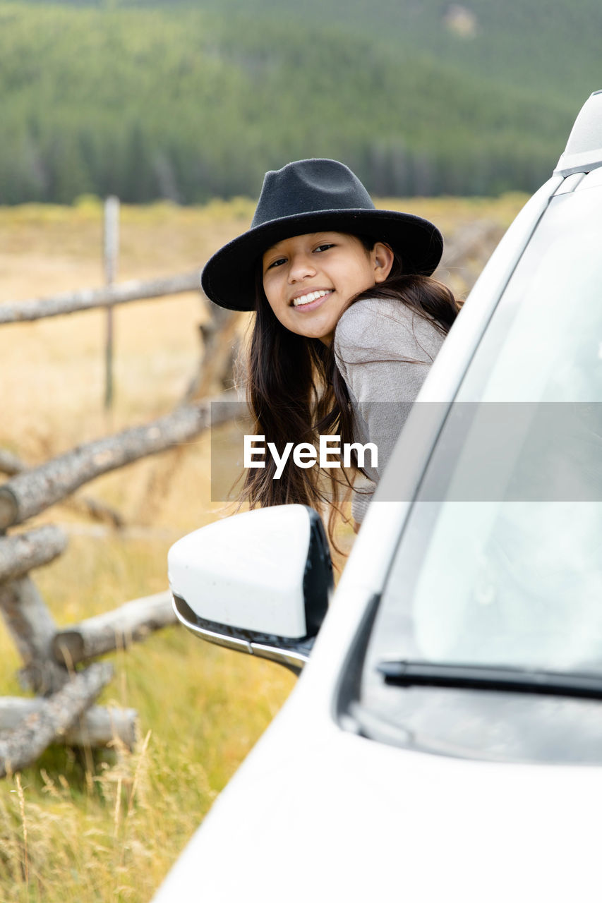 Young hispanic girl looking out passenger side of a white car