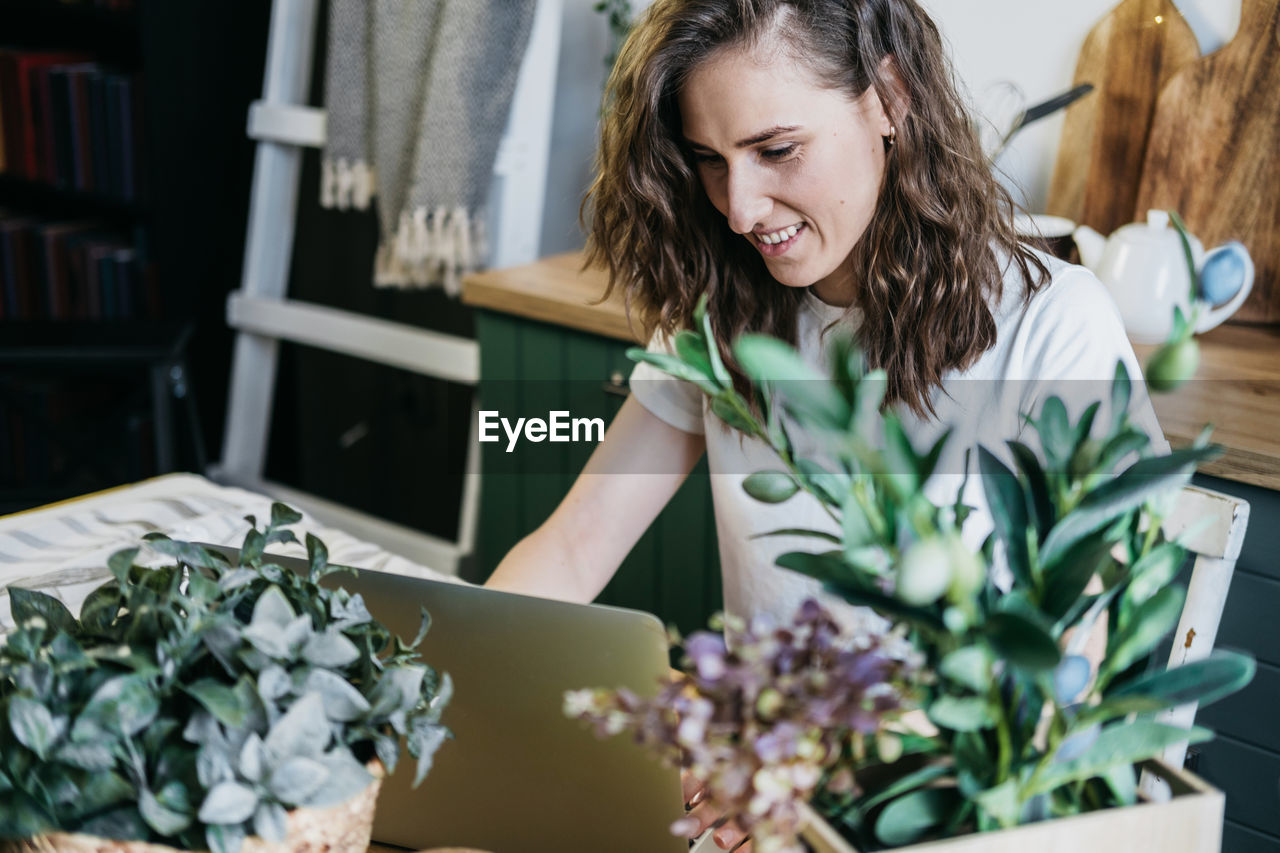 Beautiful woman in the kitchen working on a laptop.