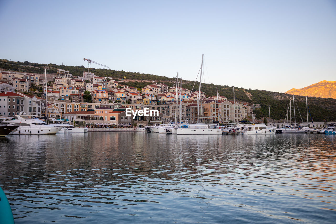 SAILBOATS MOORED IN HARBOR AGAINST CLEAR SKY