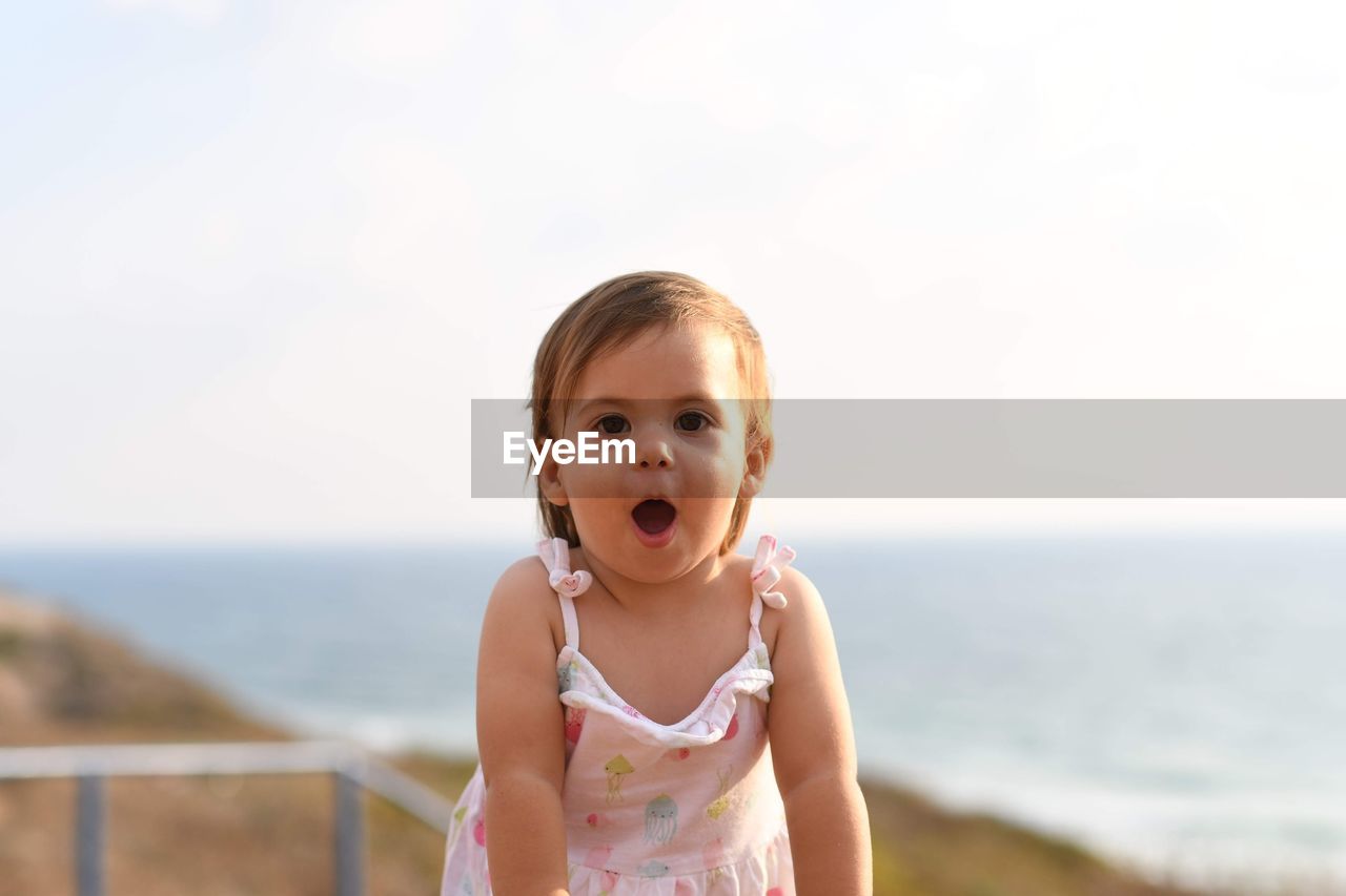 Portrait of cute girl standing against sky