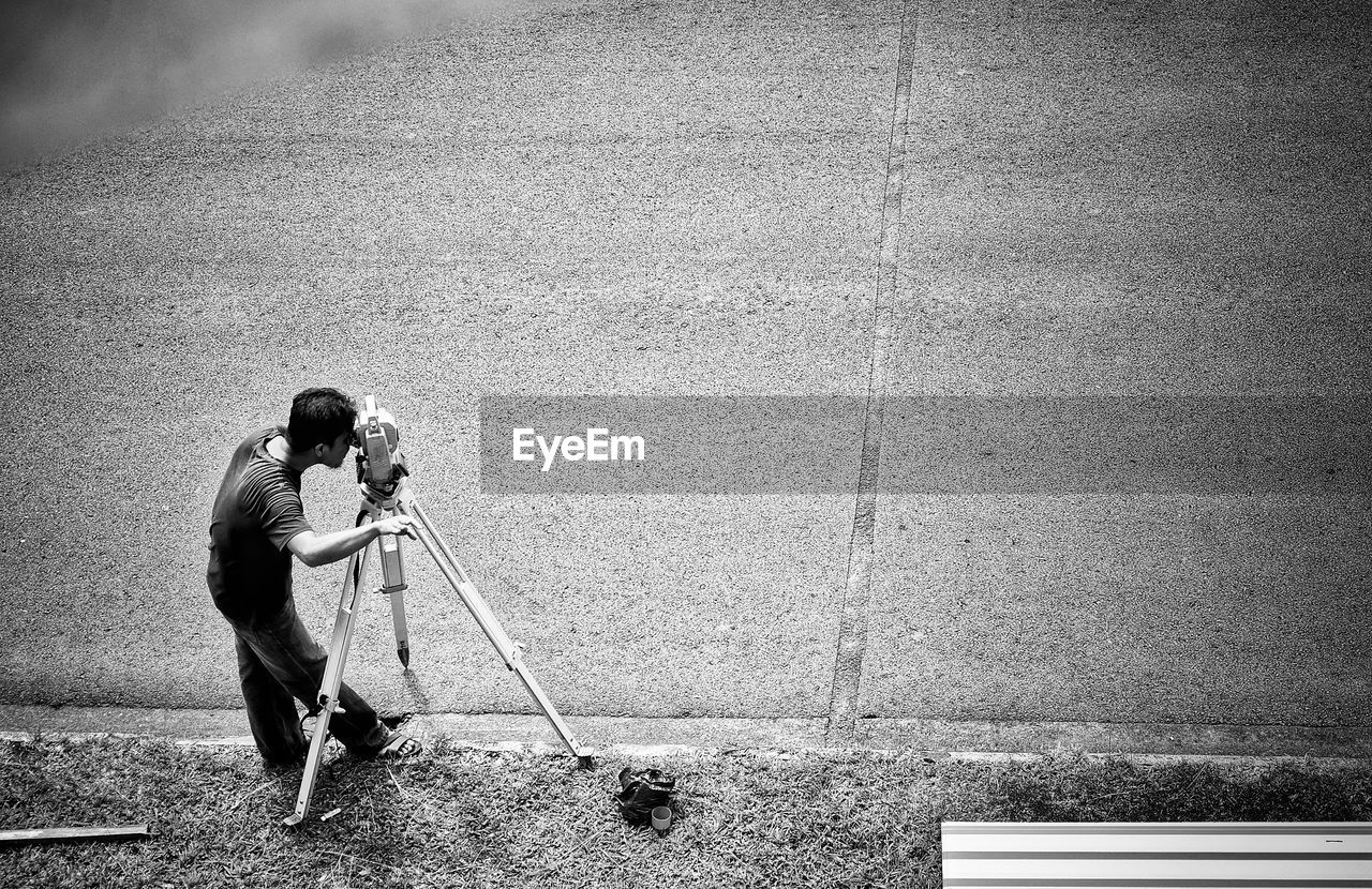 High angle view of man using theodolite on footpath