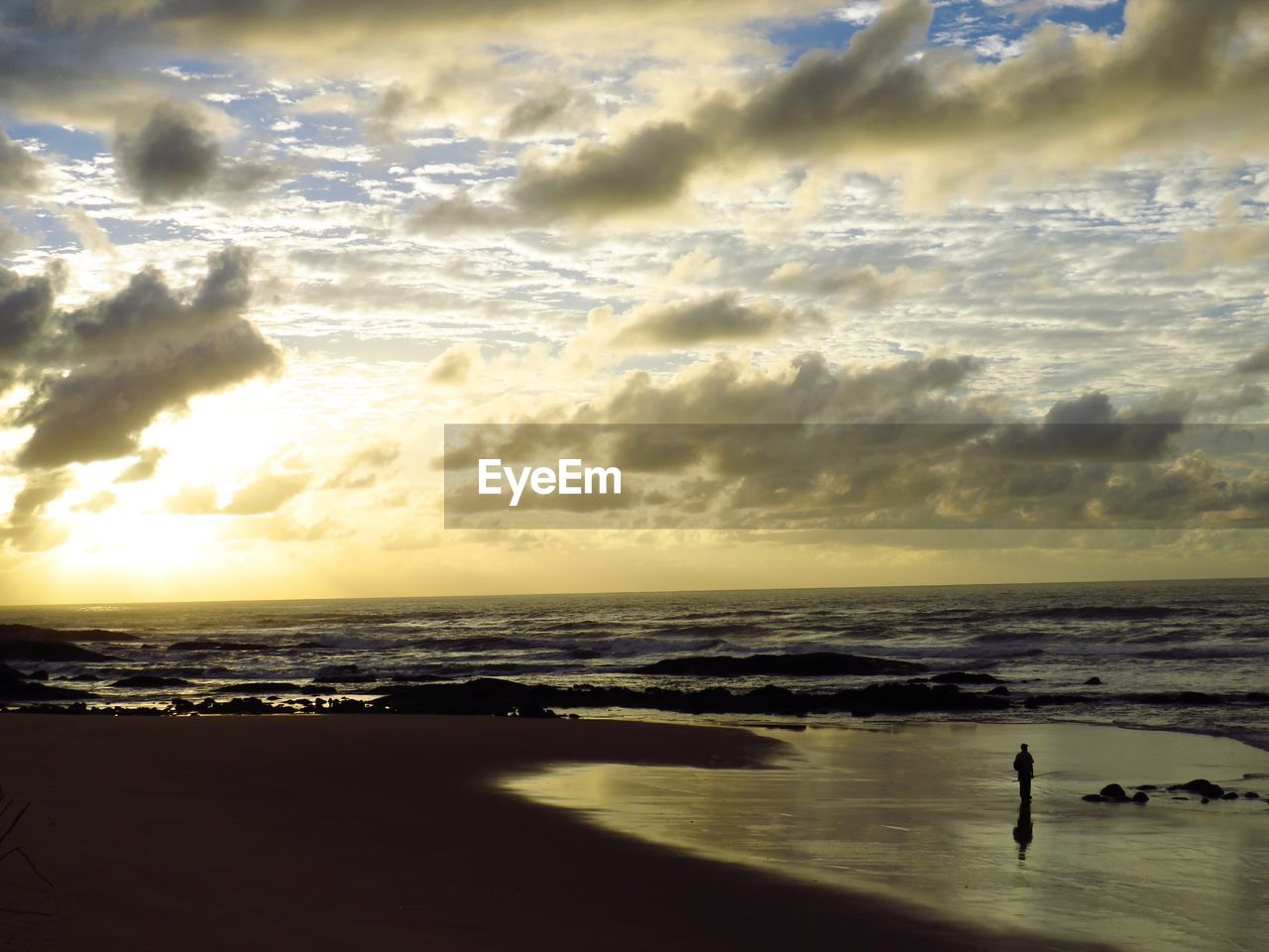 VIEW OF BEACH AGAINST CLOUDY SKY