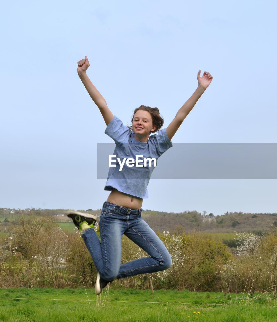 Teenage girl jumping against sky