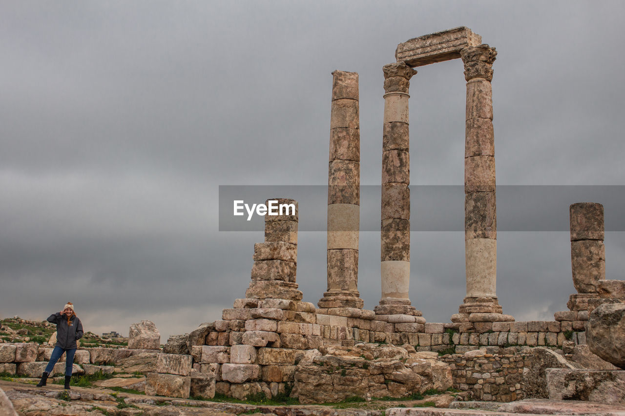 Woman standing at historic building against sky