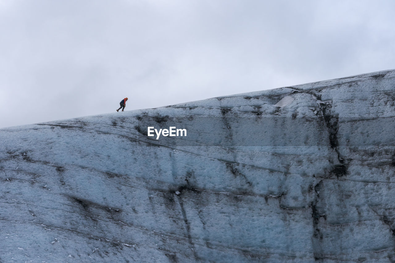 Cropped unrecognizable heaven ice formation of vatnajokull glacier with tourist located against cloudy gray sky on winter day in iceland