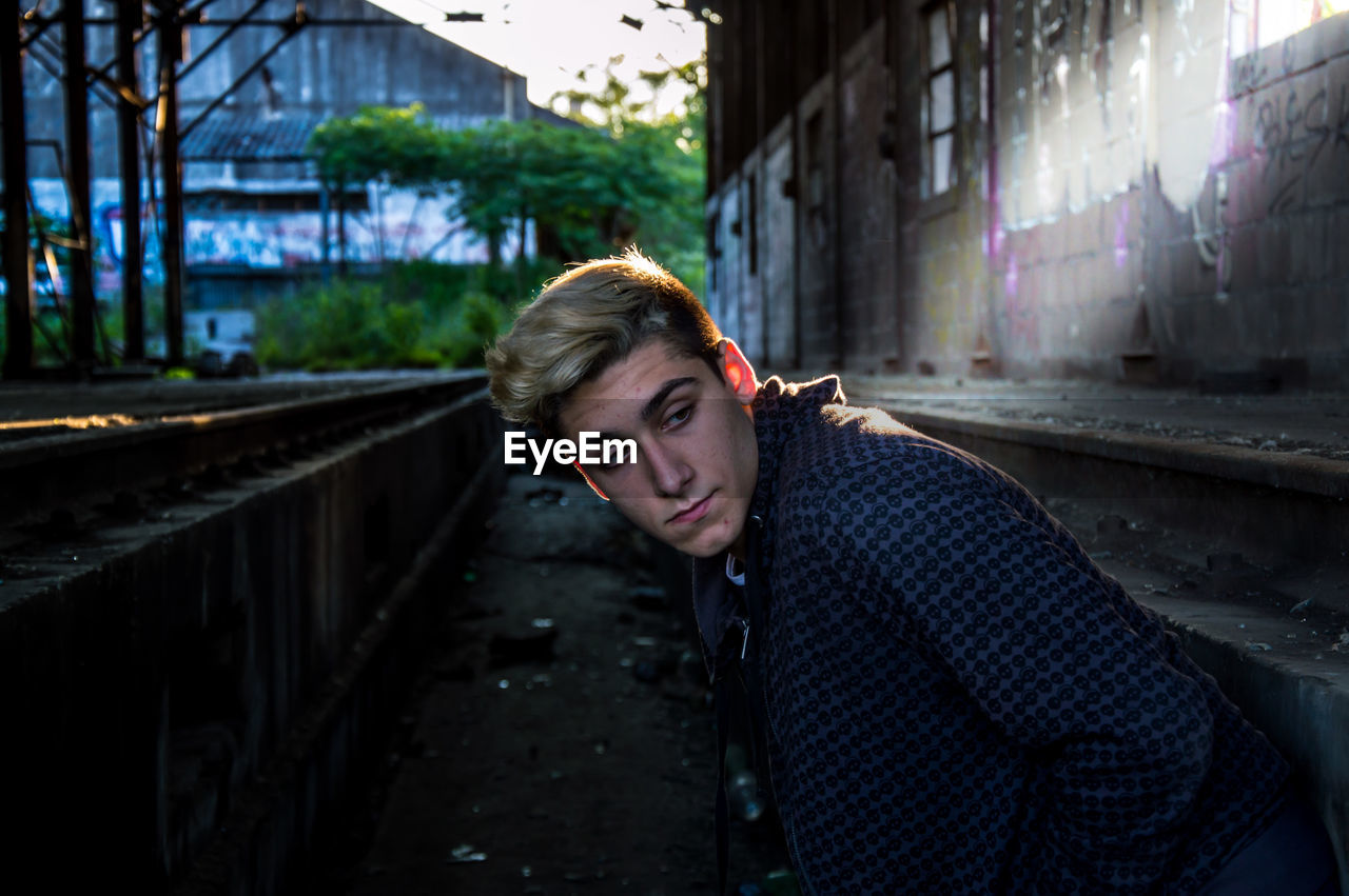 Thoughtful teenage boy standing in abandoned railroad station