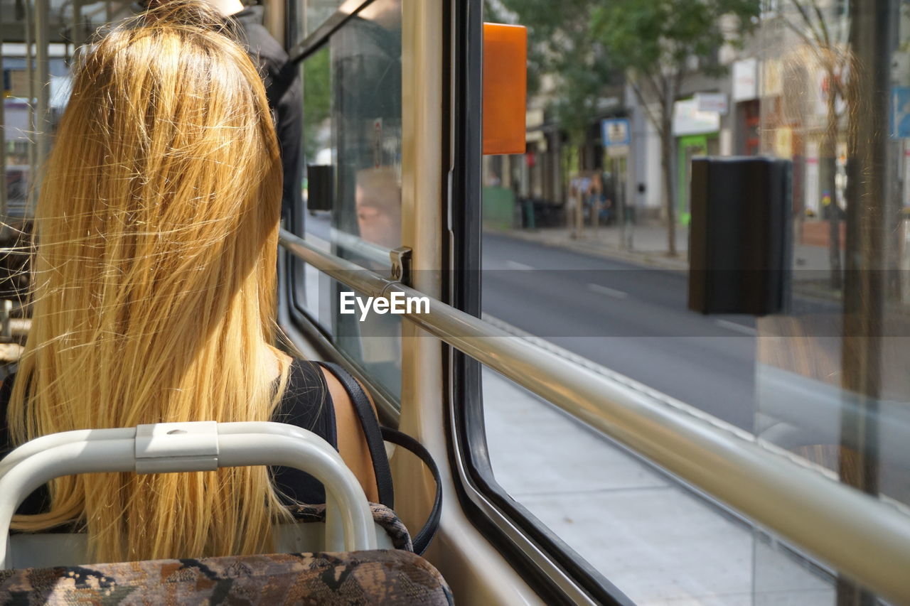 Rear view of woman with blond hair traveling in bus