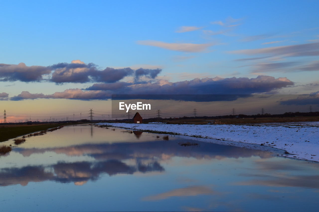 reflection, sky, water, dawn, cloud, morning, sea, beauty in nature, nature, scenics - nature, sunrise, shore, horizon, tranquility, tranquil scene, environment, blue, outdoors, landscape, land, reservoir, ocean, wave, no people, idyllic, sunlight, non-urban scene, waterfront, architecture