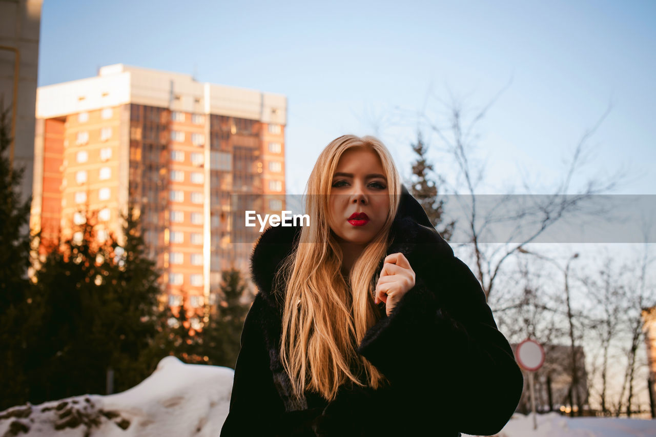 Portrait of woman in warm clothing against buildings