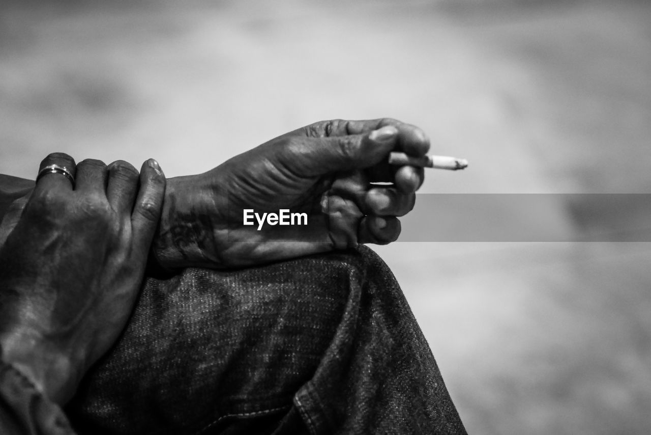 Midsection of person holding cigarette outdoors