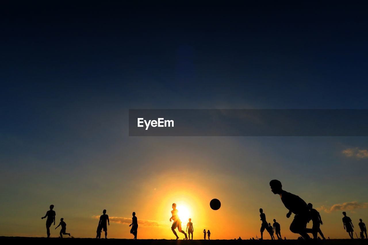 Silhouette people playing soccer sky during sunset