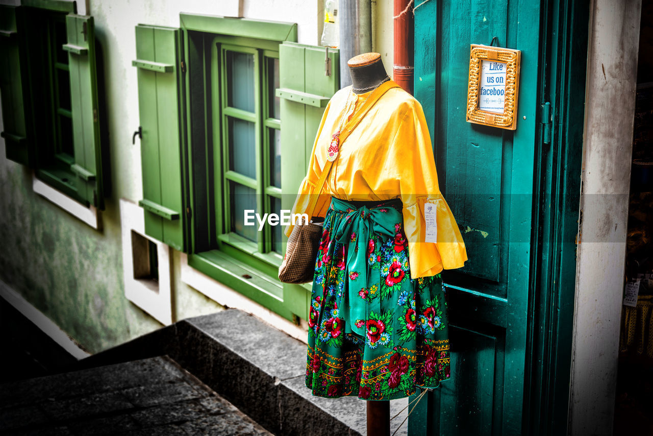 REAR VIEW OF WOMAN HANGING AGAINST YELLOW BUILDING