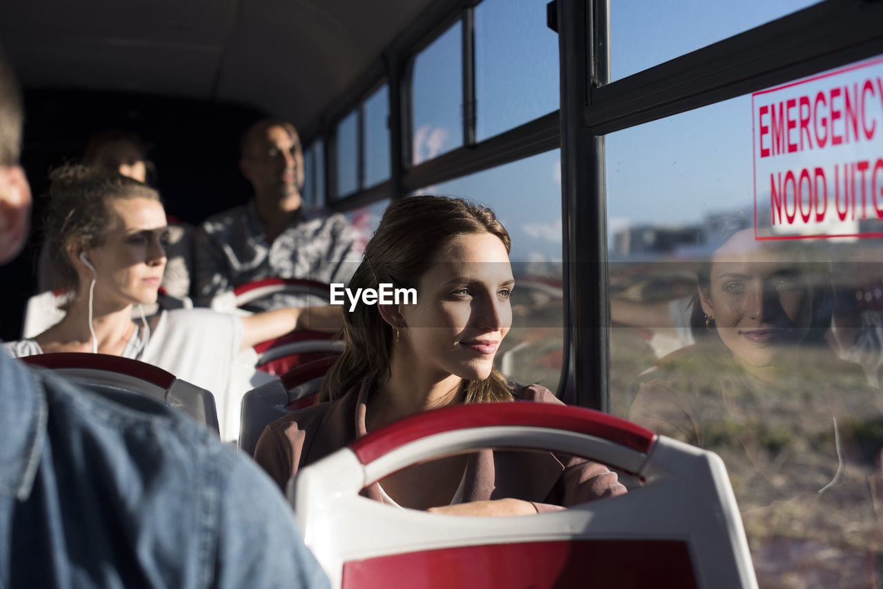 Passengers looking through window while traveling in tour bus