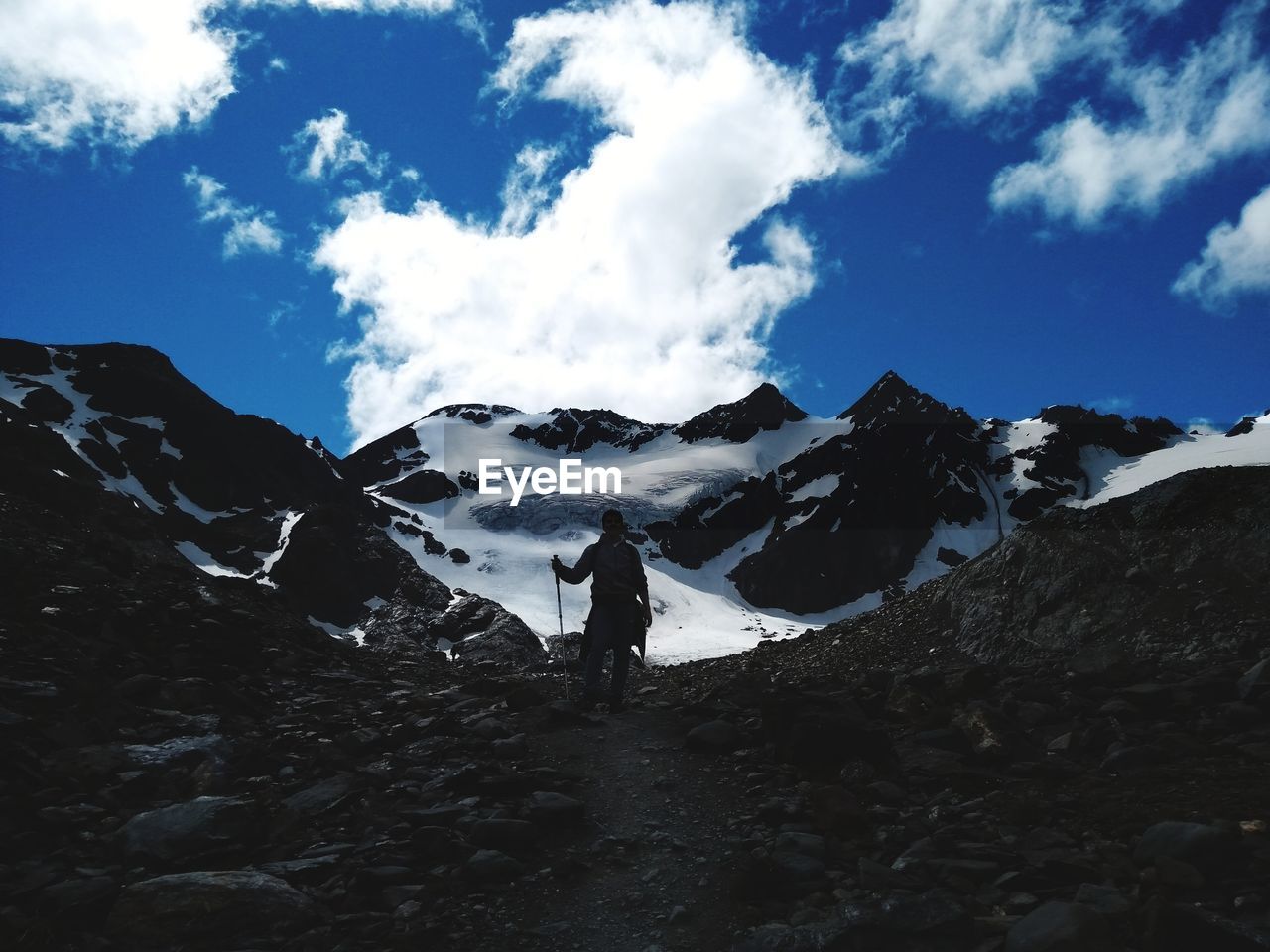 Low angle view of silhouette man hiking on snowcapped mountain against sky