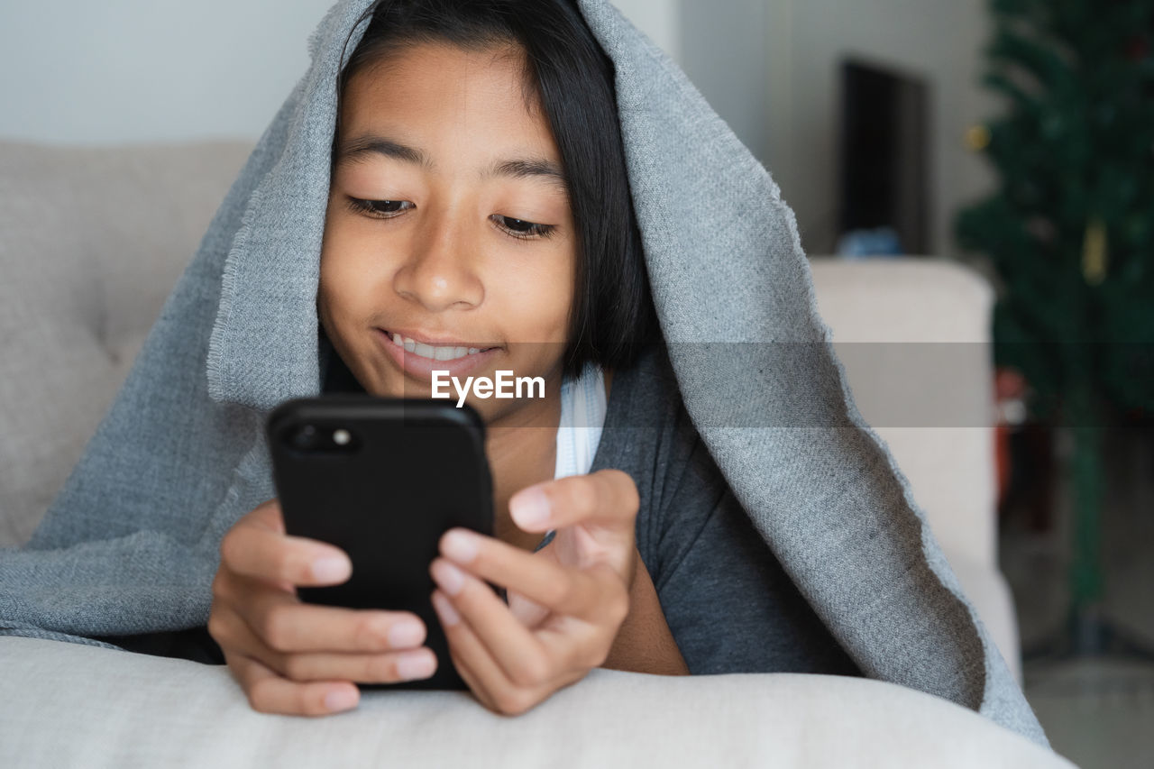 Close-up of girl using mobile phone at home