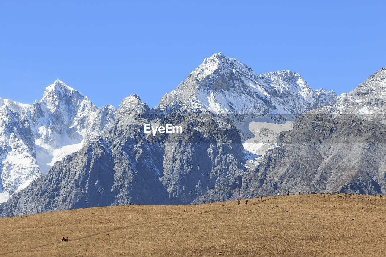 Low angle view of snowcapped mountain against clear blue sky