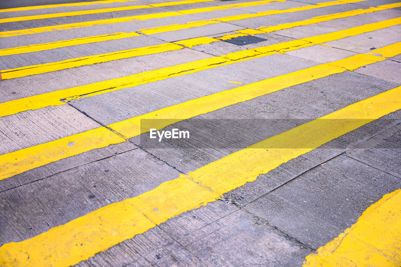 HIGH ANGLE VIEW OF YELLOW ZEBRA CROSSING ON STREET
